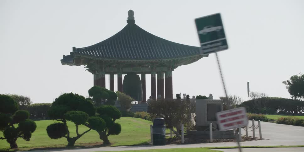 Oriental building sits in a park with three people nearby