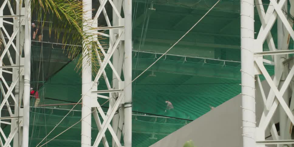 Golfers stand in individual areas practicing their swings in a structure