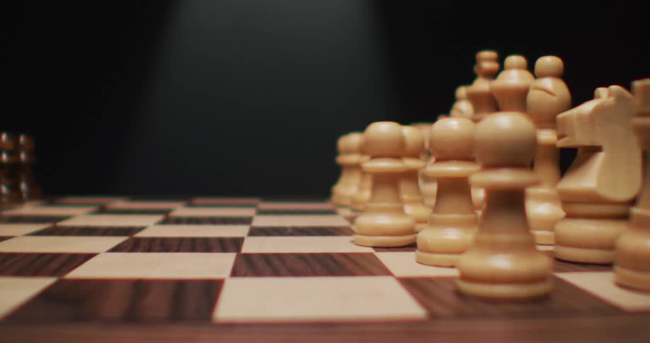 A white pawn moves up one space on a wood grain chessboard