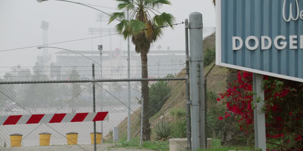 Chain link fence bordered by welcome sign blocks access to fog covered dodger stadium