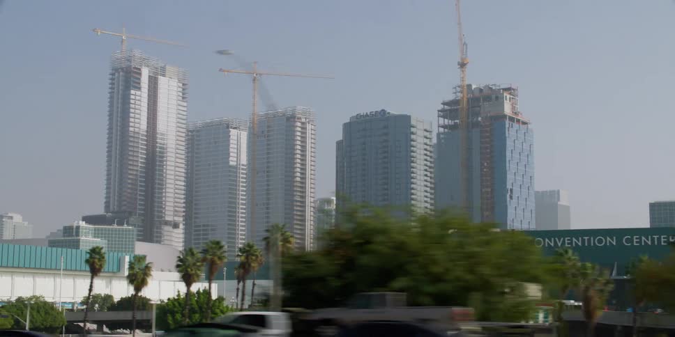 Distant view of cranes constructions and high rise buildings seen from moving car