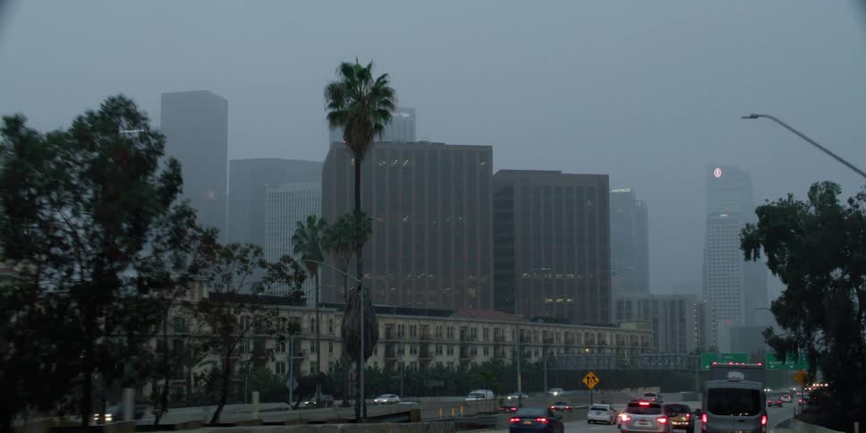 People are driving cars near a downtown city at dusk
