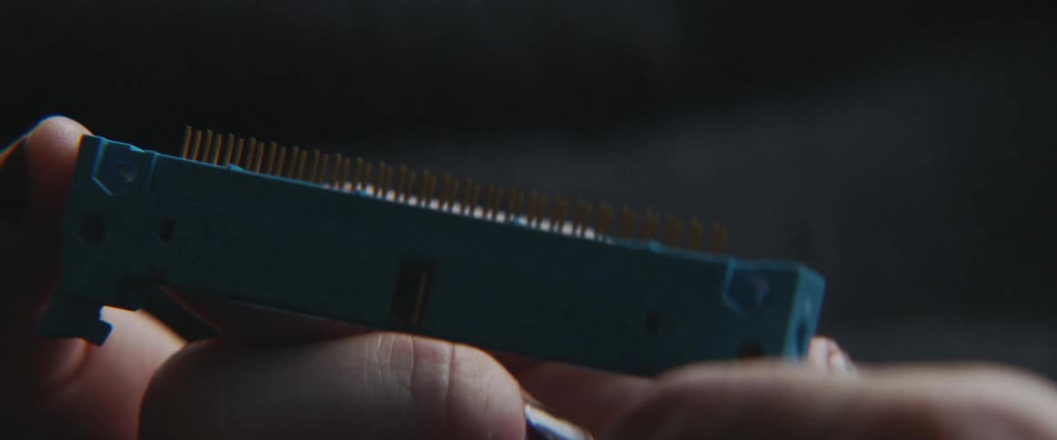 A woman holds and examines a small electrical device with pins