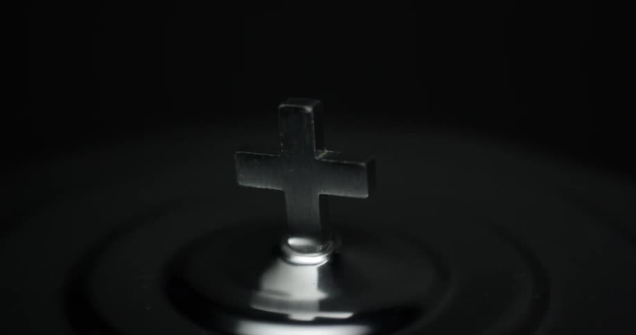 A silver cross sits in the dark