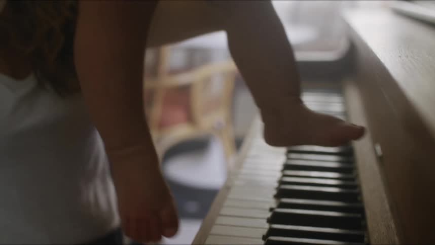 A mother and her baby sitting at a piano
