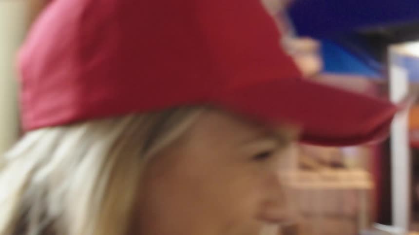 A woman smiling and eating ice cream as she walks past brightly lit stalls