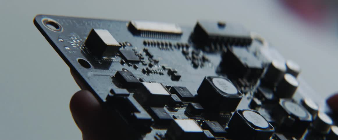 A hand holding and tilting an electronic circuit board