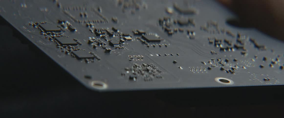 A person holds and examines a circuit board