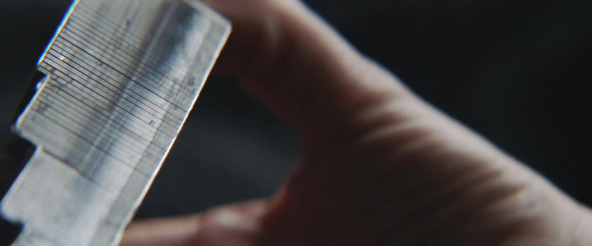 A man turns a piece of metal around in his hand