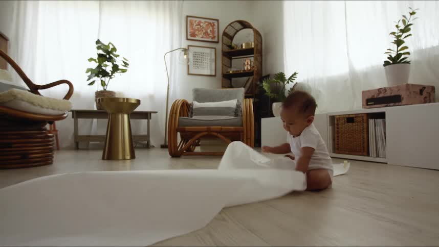 An infant plays with a long roll of paper in a home
