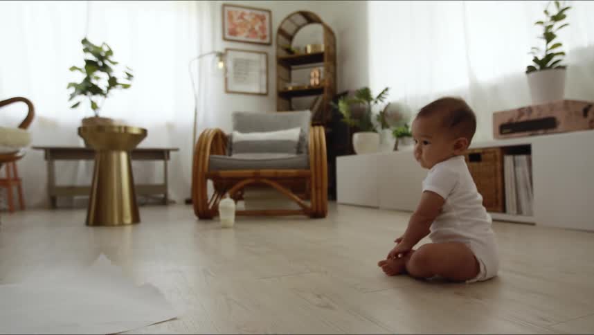 A baby grabs at a towel on the ground