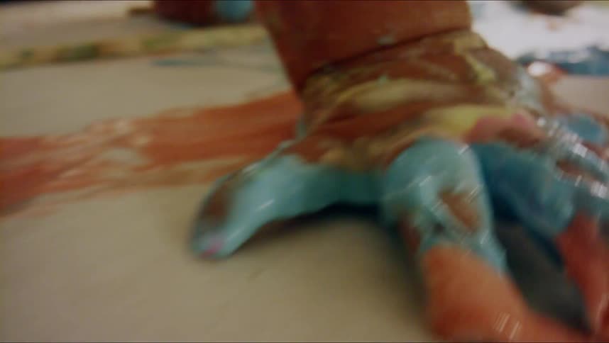 A baby crawls through paint smeared on butcher paper