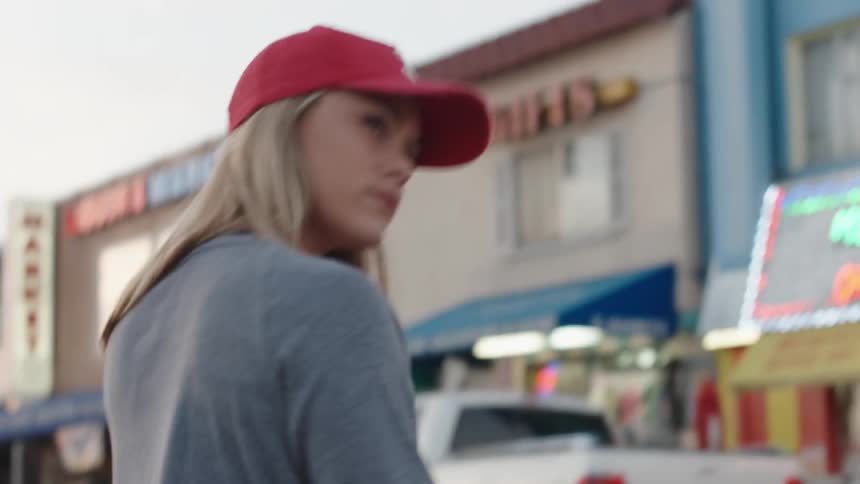 A woman crossing a street towards some shops