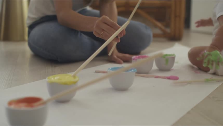A woman handing paint to her baby