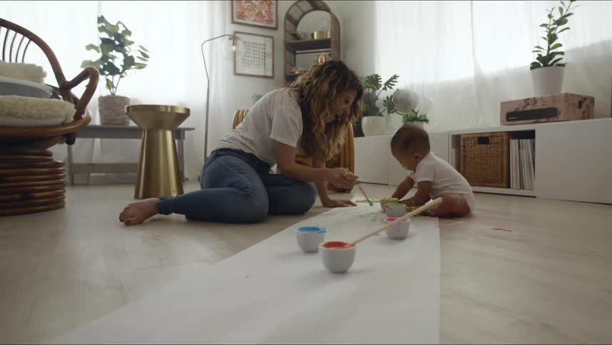 Woman and baby do some painting while sitting on the floor