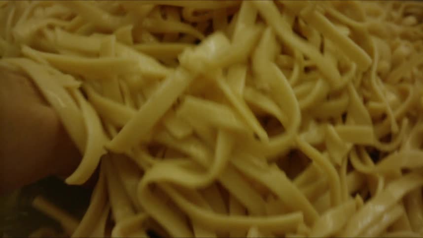 A person mixing pasta in a big pot