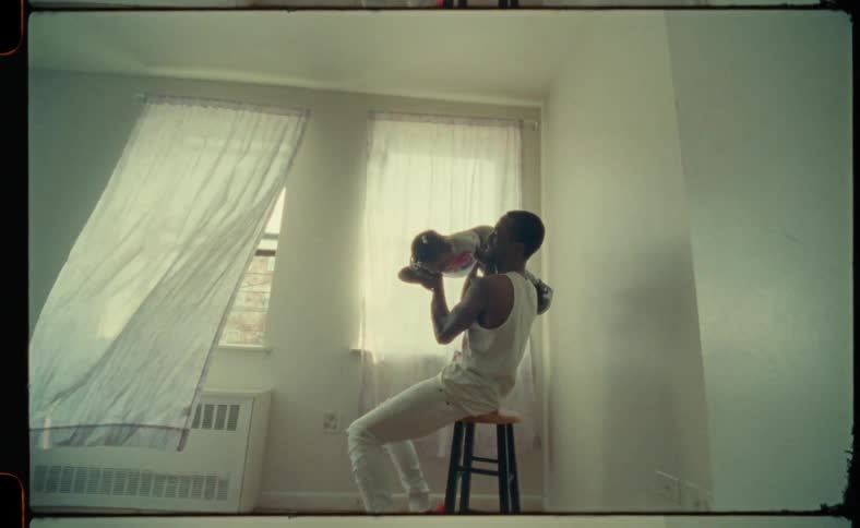 Man holds a little girl up with his hands as he sits on a stool