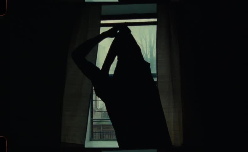 Man stading next to the window looking outside while stretching his arms and body
