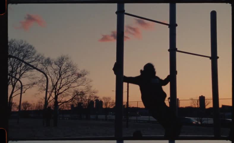 A man hangs upside down on bars at a public park