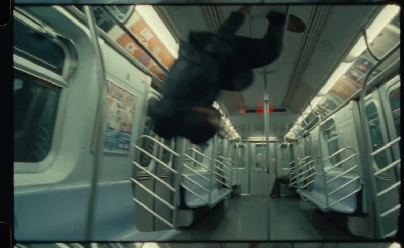 A man swings around and dances in an empty moving train car