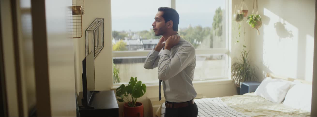 A man is putting on a suit indoors