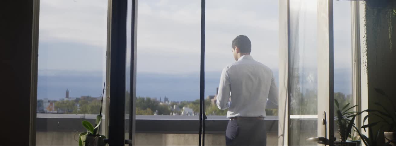 A man is walking outdoors onto his balcony