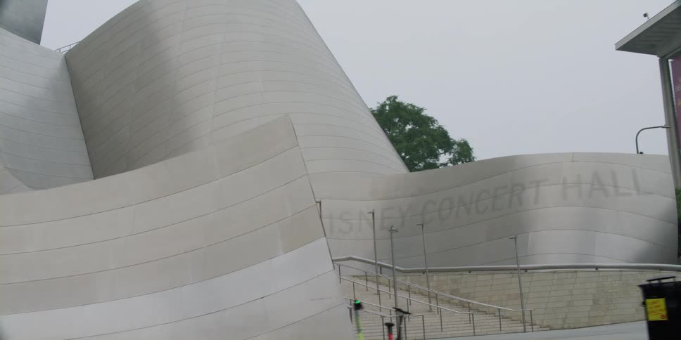 A vehicle drives past a concert hall with an abstract design