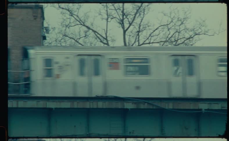 A train is traveling across a bridge near buildings