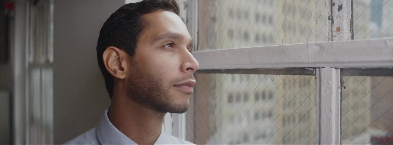 A man is looking out a window in a downtown city