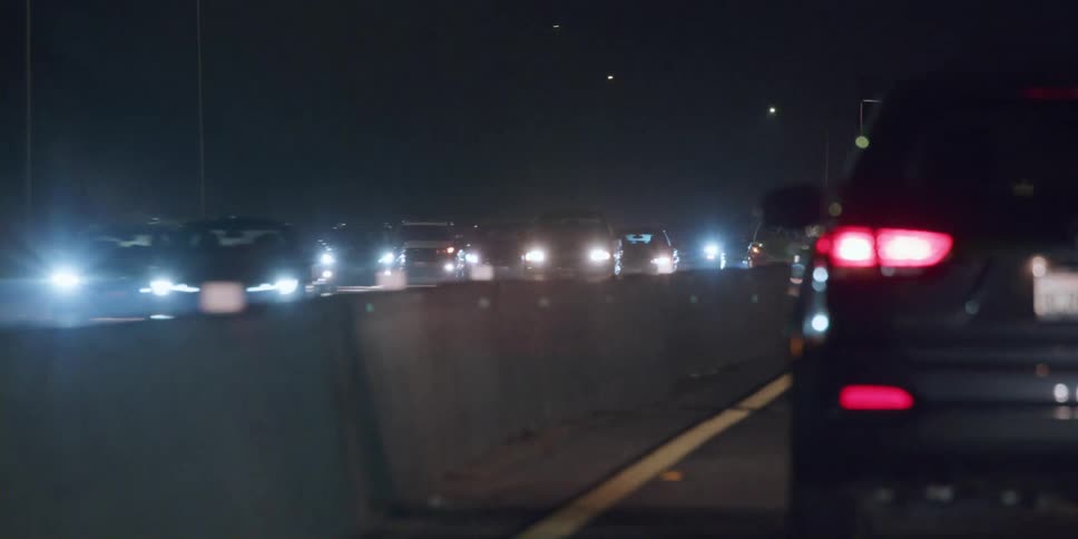 Traffic flows on both sides of concrete divided controlled access highway at night
