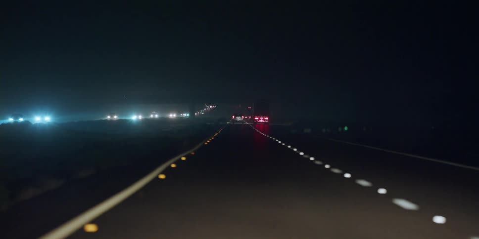 Vehicles driving down a highway at night