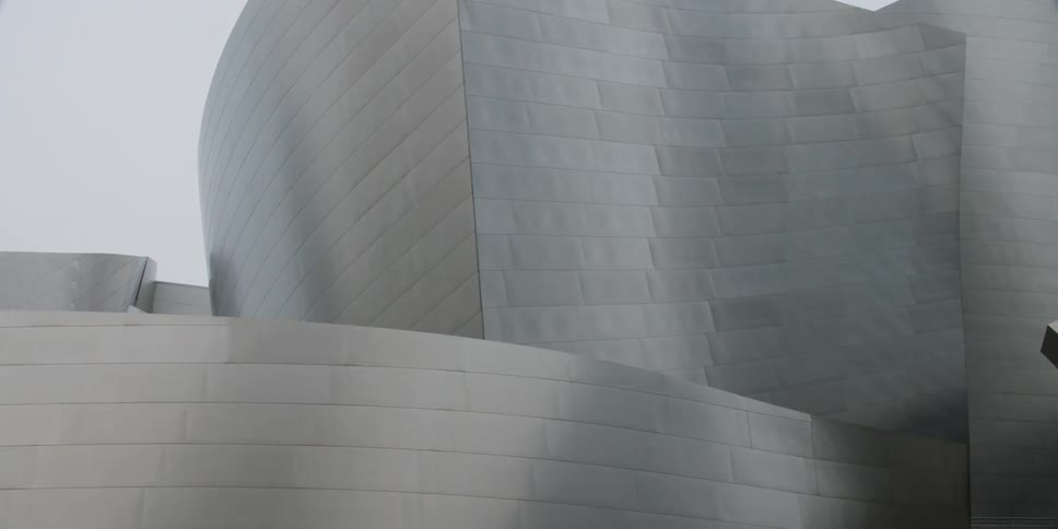 Metallic walls ripple over sculpted surfaces near building
