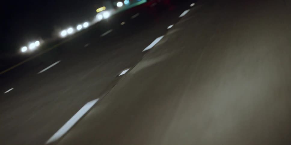 Traveling on a highway looking down at the lanes on the road and the lights on the automobiles