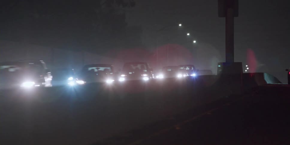 Cars are driving on a divided highway at night