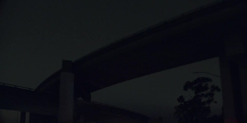 Automobiles are traveling on a freeway at night and go under and overpass