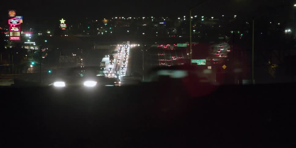 View of dense highway traffic at night as seen from a vehicle traveling on an overpass