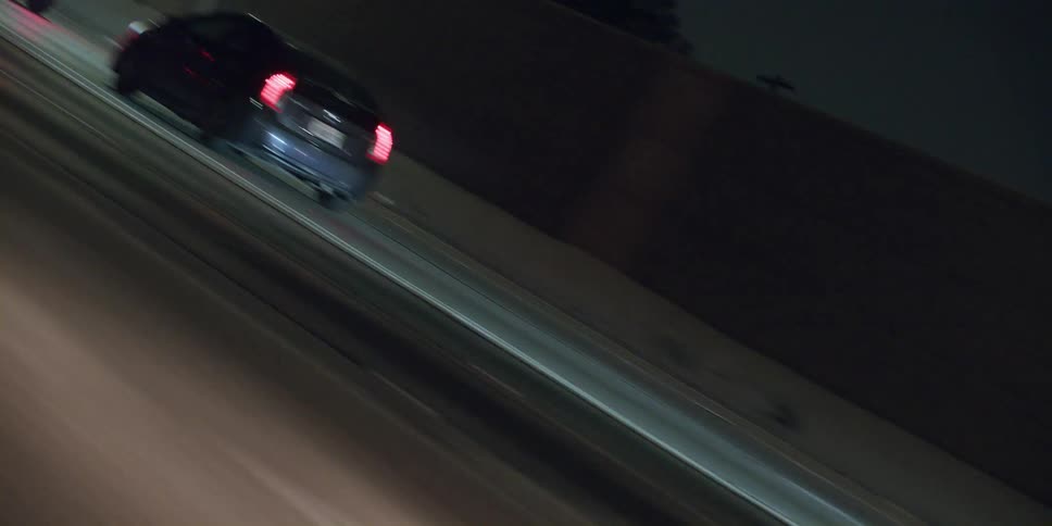 Cars are driving on a highway at night