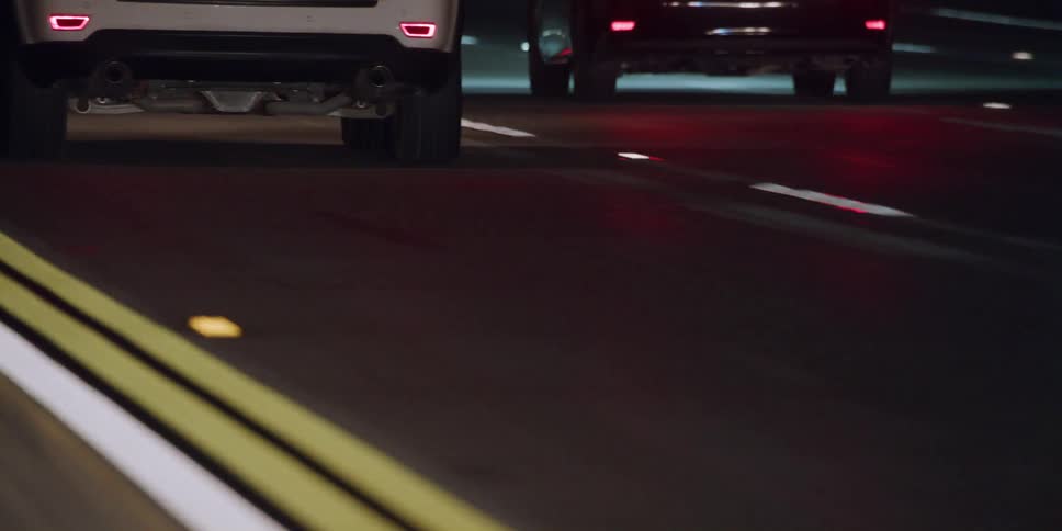 A view of the ground while traveling in highway traffic at night