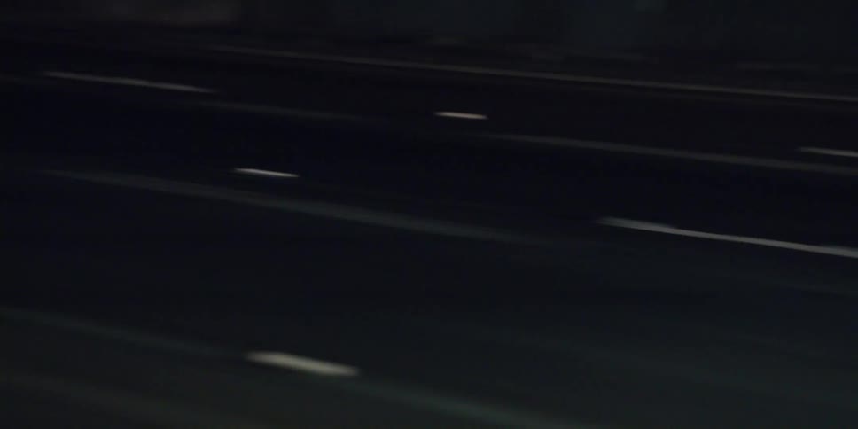 Cars are driving fast on a road at night