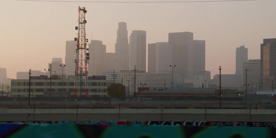 A utility tower stands tall with city buildings seen through the fog