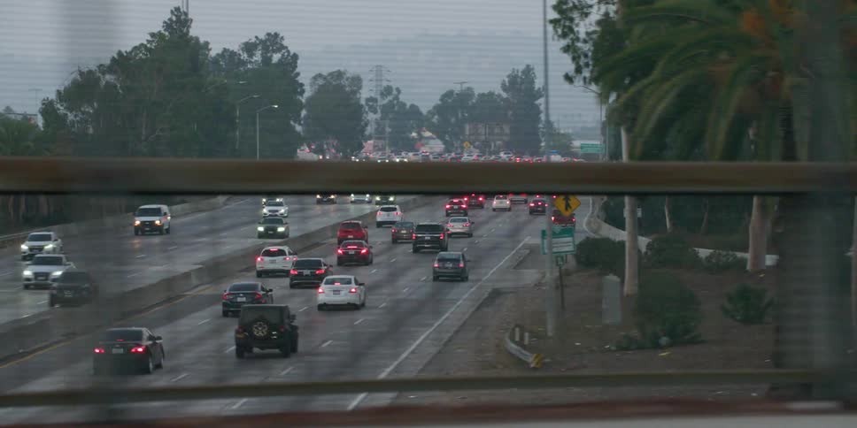 Cars are driving on a divided highway at dusk
