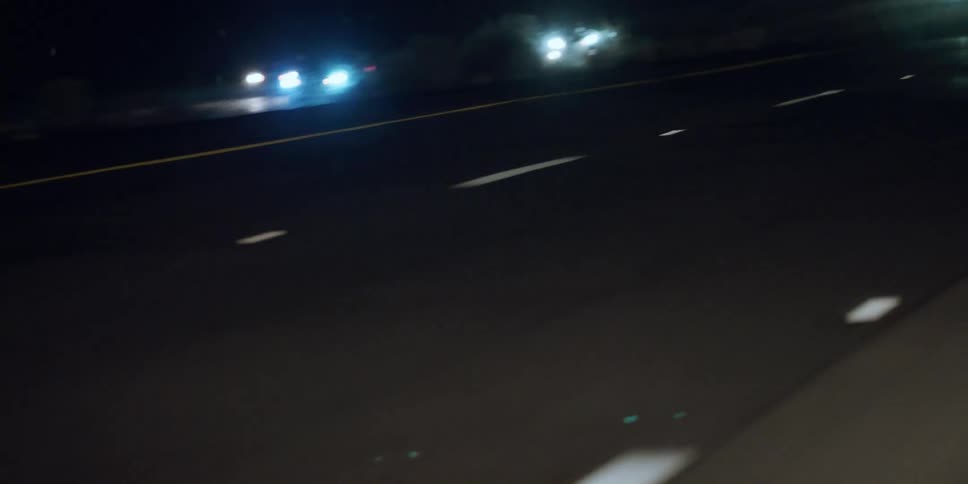 Traveling on a highway looking down at the lanes on the road and the lights on the automobiles