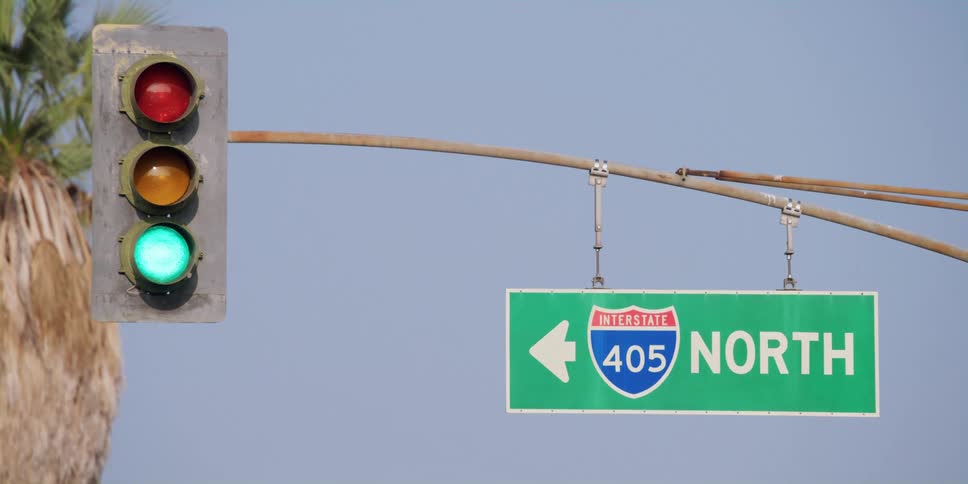 A sign for interstate 405 north is next to a traffic light