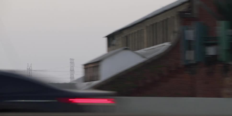 A helicopter is flying high above town and utility towers as traffic moves on the road