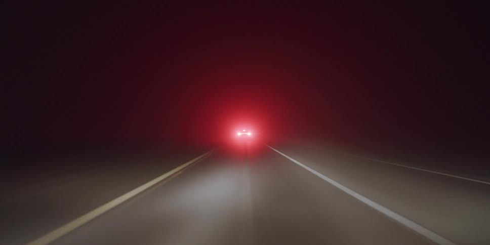 Trucks and cars are traveling on a road at night