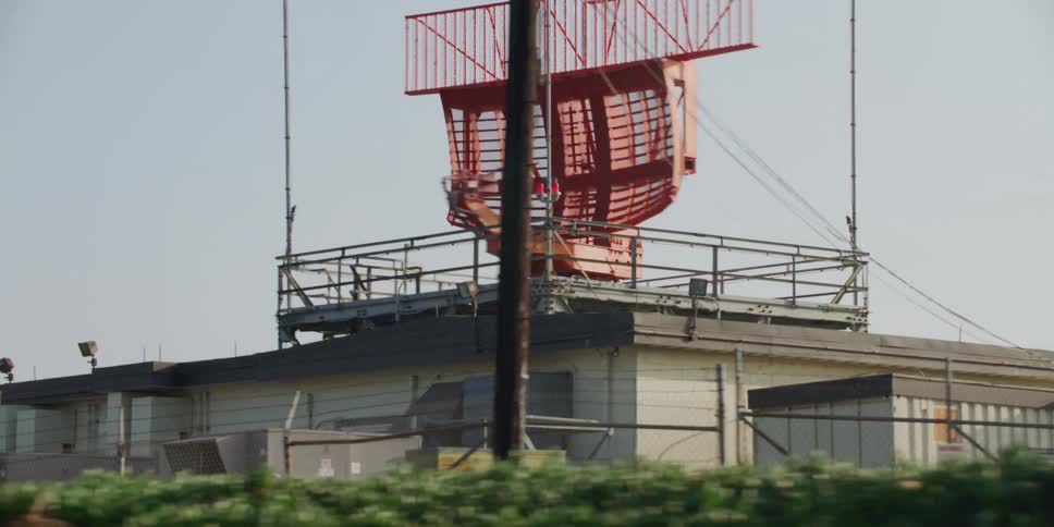 Red radar array in platform on top o building rotates as it scans