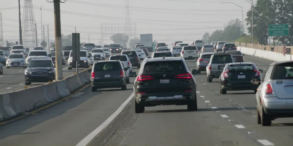 Automobiles are traveling slowly on a busy highway