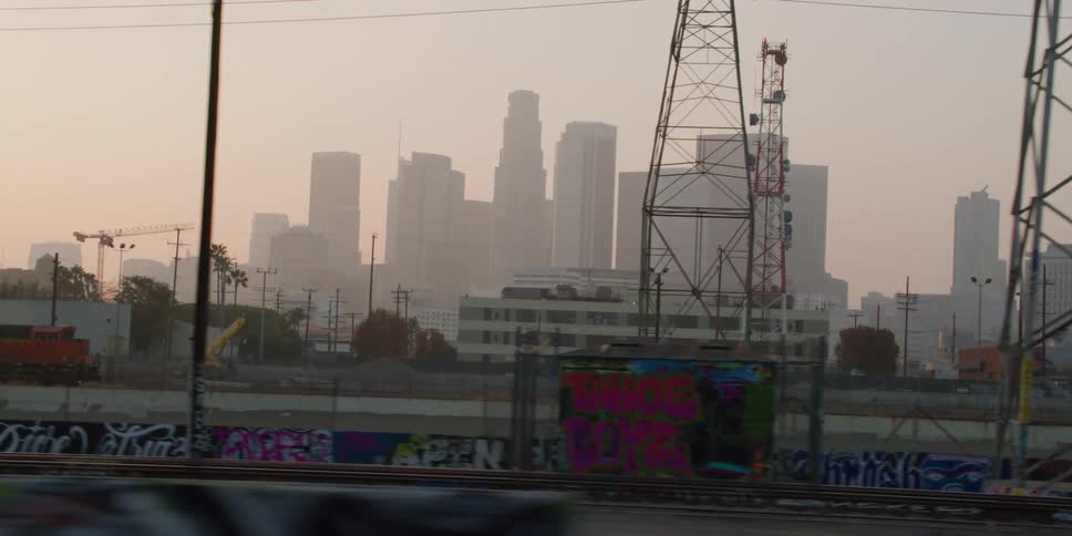 Electrical towers and construction cranes and a train in front of a city skyline