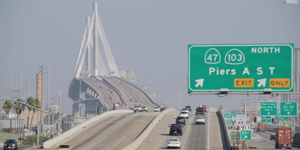 Vehicles drive on a multi lane highway that heads onto a bridge