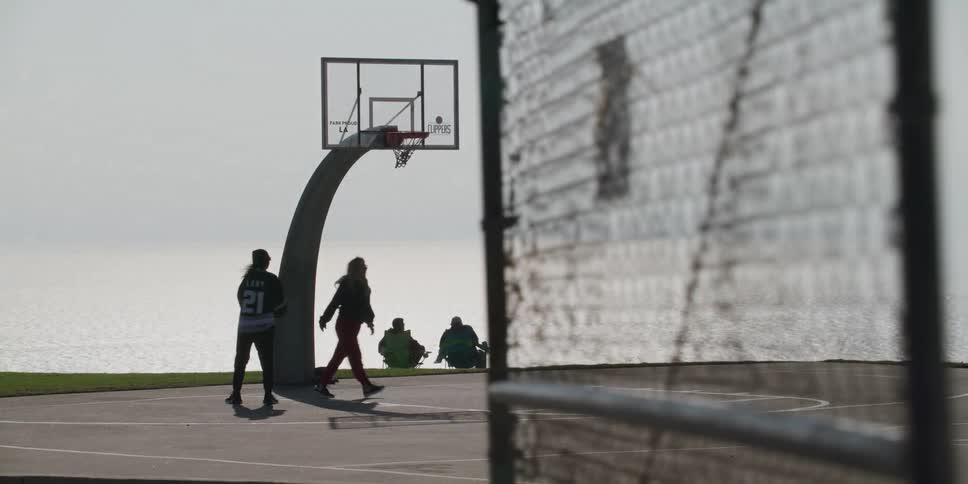 Two friends shooting hoops on basketball court at the beach